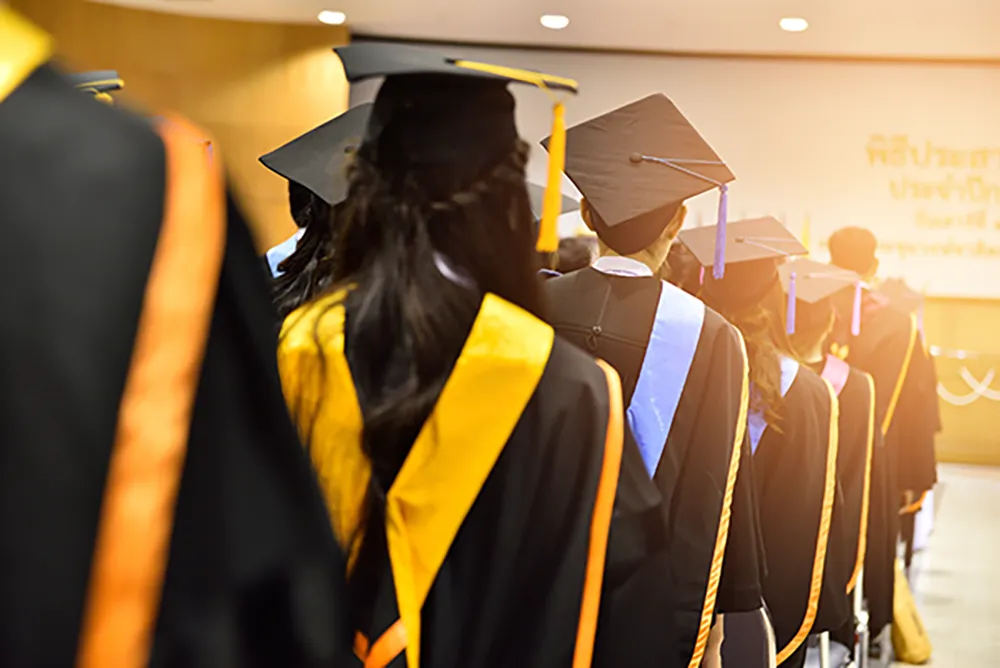 College university graduates in a line to receive their diplomas wearing graduation regalia